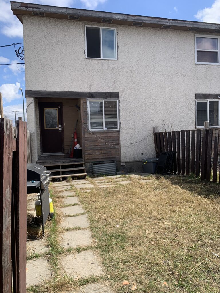 A clean back yard with grass and a stone path